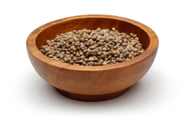 dried hemp seeds in a wooden bowl - hemp seed heap white imagens e fotografias de stock