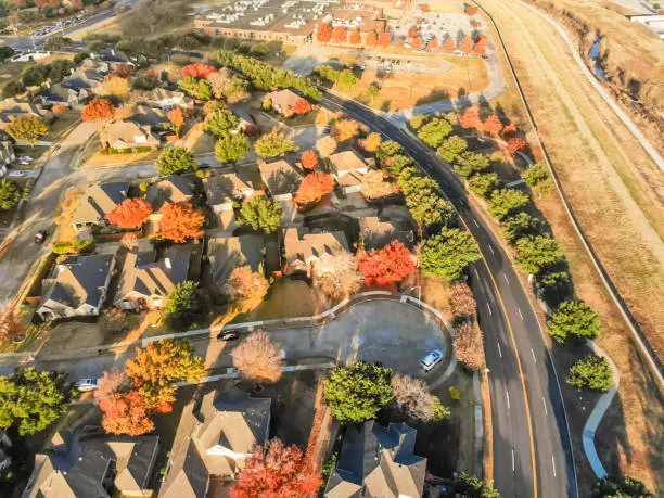 Aerial view parkside neighborhood with cul-de-sac (dead-end) street near Dallas, Texas. Flyover urban sprawl in autumn morning with colorful fall foliage leaves