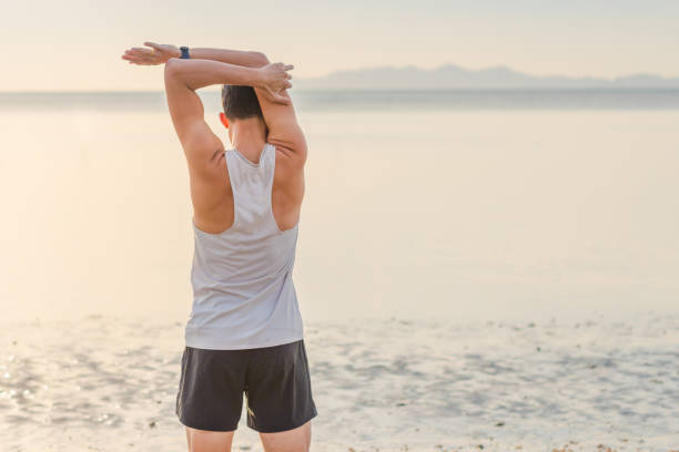 istock Young asian man doing yoga exercise at sunset beach 1093102508