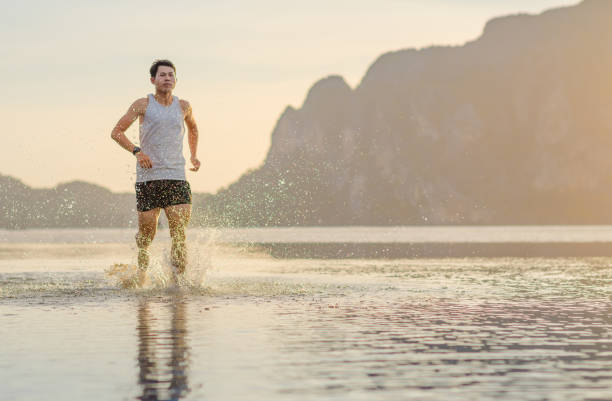 istock Young asian man running on beach with sunset in background 1093108254