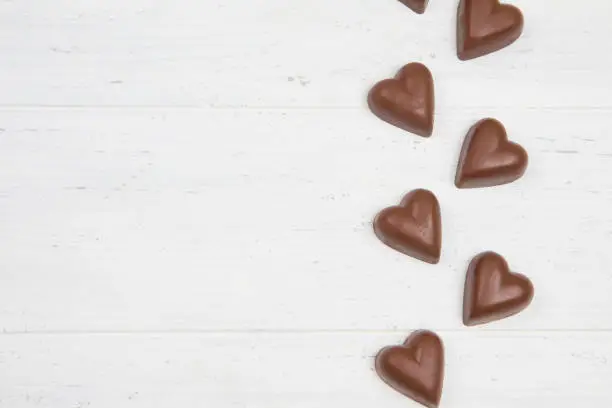 Chocolate hearts on white wooden background