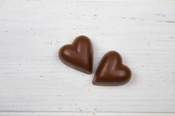 Closeup of two chocolate hearts. White wooden background. Love