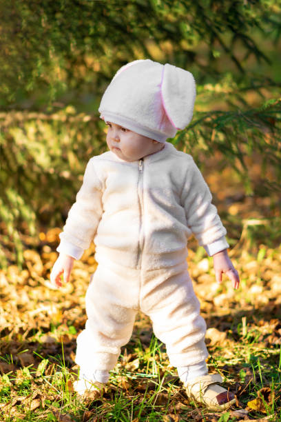 chica en traje de conejo de pie en el bosque y mirando lejos del cabrito - rabbit baby rabbit hare standing fotografías e imágenes de stock