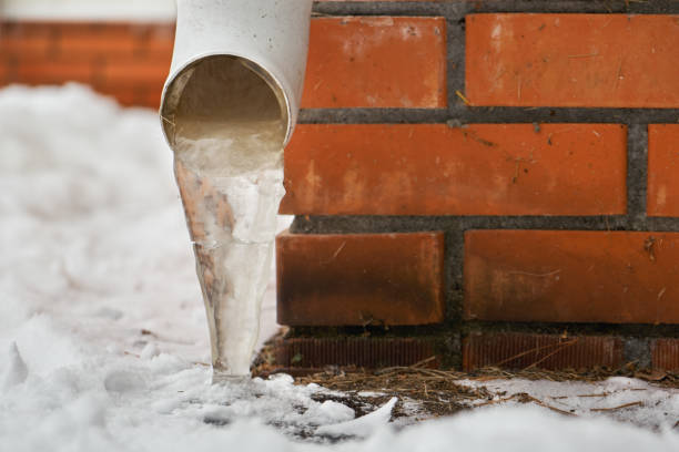 Drain pipe with frozen stream of water near house brick wall Drain pipe with frozen stream of water near brick wall of a cottage outdoors in winter frozen water stock pictures, royalty-free photos & images