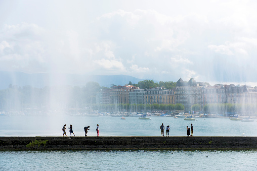 People are walking under Jet D'eau in Geneva, Switzerland
