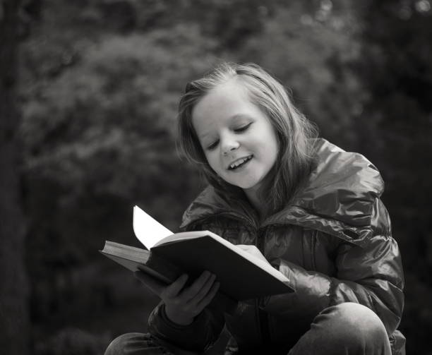 istock Happy Girl Reading Book While Sitting In Park 1093135064