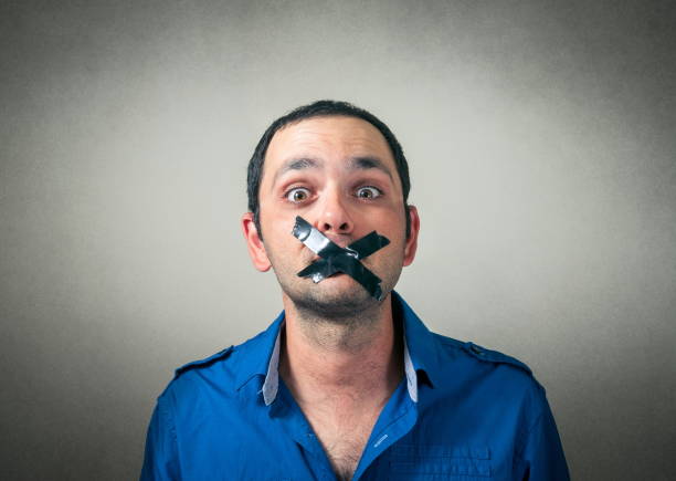 porträt eines verängstigten mannes im mittleren erwachsenenalter mit schwarzem klebeband auf dem mund vor grauem hintergrund - human mouth duct tape covering adhesive tape stock-fotos und bilder