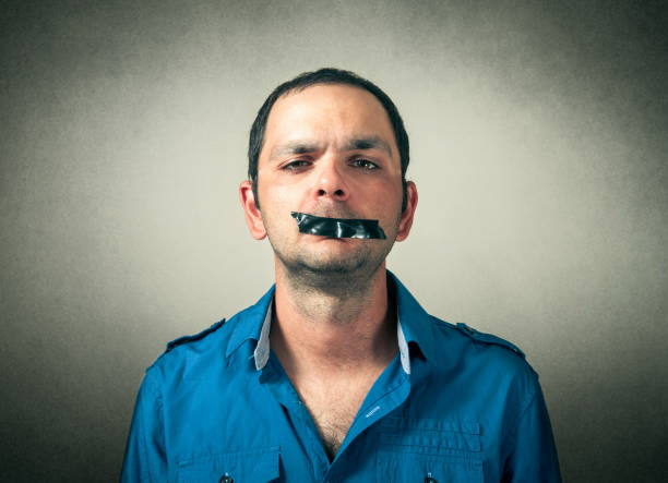 porträt eines selbstbewussten mittelerwachsenen mannes mit schwarzem klebeband auf dem mund vor grauem hintergrund - human mouth duct tape covering adhesive tape stock-fotos und bilder