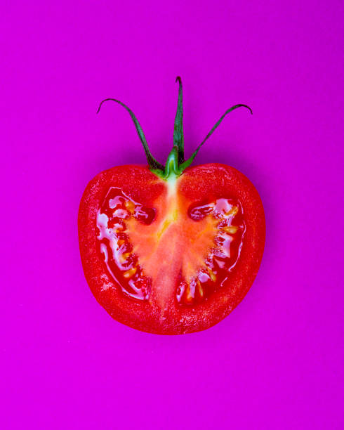 istock Single Half Salad Tomato with stalk pop Art style centred from above on bright Purple coloured background 1093139630