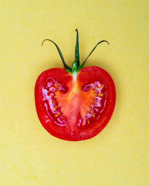 istock Single Half Salad Tomato with stalk pop Art style centred from above on bright Yellow coloured background 1093140784