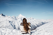 Woman and dog enjoying the view of winter Swiss alps