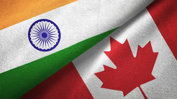 Photo of Canada and India two flags together textile cloth fabric texture