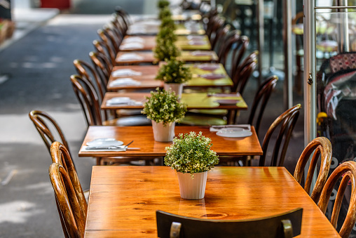 A row of chairs and tables at a outdoor cafe on Lygon Street, Carlton, Melbourne, Australia