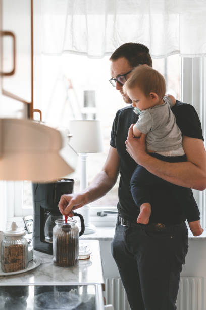 Stay at home father making coffee with his son in the morning A stay at home father in Sweden is taking care of his young son in his apartment. He is standing in the kitchen making coffee in the morning. scandinavian ethnicity stock pictures, royalty-free photos & images