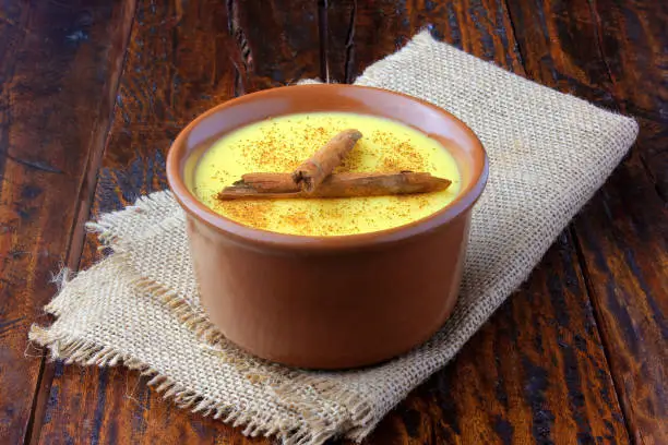 Photo of Curau, cream of corn sweet and dessert typical of the Brazilian cuisine, with cinnamon placed in ceramic bowl on wooden table. Copy space. Close-up