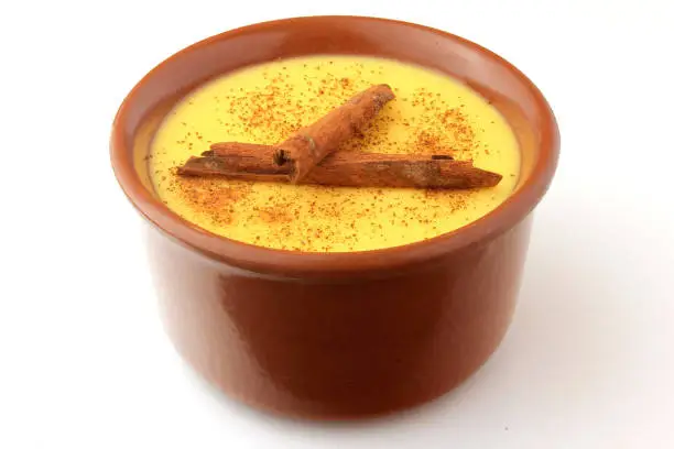 Photo of Curau, cream of corn sweet and dessert typical of the Brazilian cuisine, with cinnamon placed in ceramic bowl on white background. Copy space. Close-up