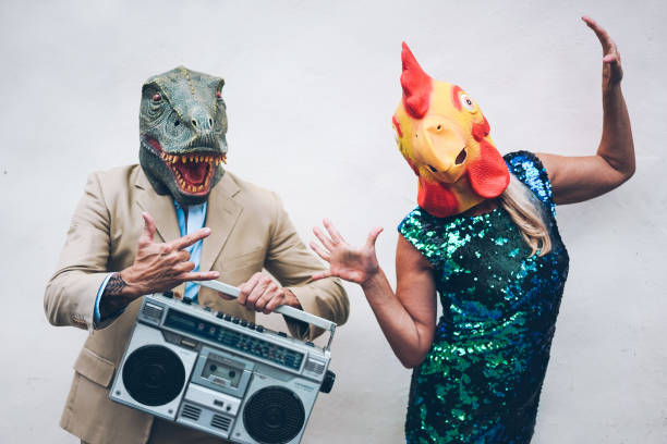 сумасшедший старший пара танцует на канун нового года партия носить t-rex и куриная маска - старые модные люди весело слушать музыку с boombox сте - эксцентричный стоковые фото и изображения