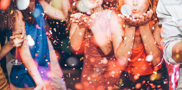 glückliche freunde werfen konfetti - jugend feiert am wochenende nacht - unterhaltung, spaß und nachtleben fest konzept - karnevalsparty im fokus zentrum mädchen hände - karneval feier stock-fotos und bilder