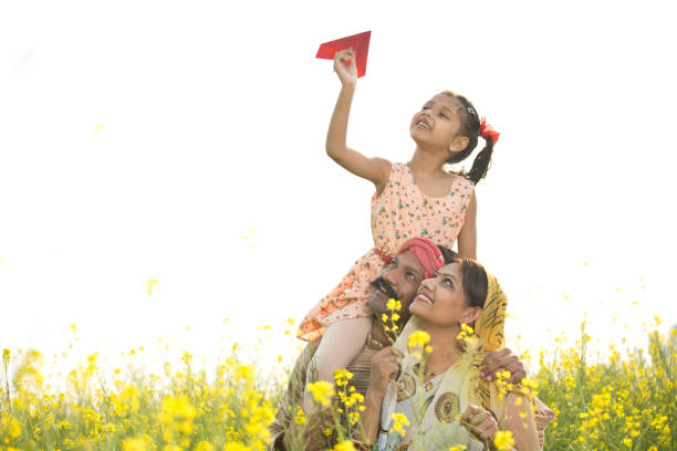 girl sitting on father's shoulder and throwing paper airplane - day asian ethnicity asian culture asian and indian ethnicities imagens e fotografias de stock