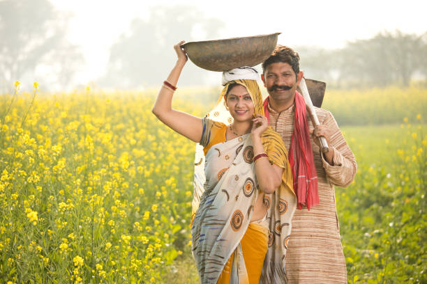 Rural couple with iron pan and hoe in agricultural field Rural Indian couple with iron pan and hoe in rapeseed agricultural field garden hoe photos stock pictures, royalty-free photos & images