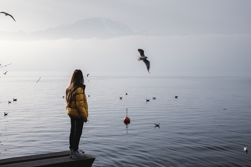 Woman enjoying the view of Swiss Alps, lake Geneva and flying birds in Montreux