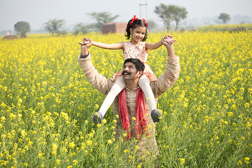 Portrait of happy rural Indian family in rapeseed agricultural field