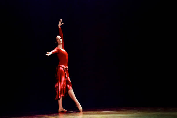 istock Woman dancing ballet on a empty stage against black background 1093201728