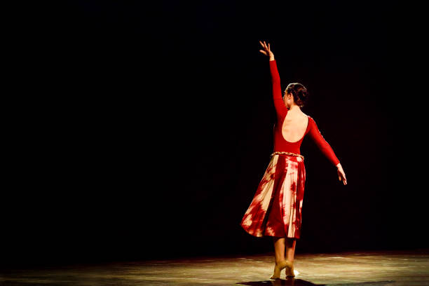 istock Woman dancing ballet on a empty stage against black background 1093201780