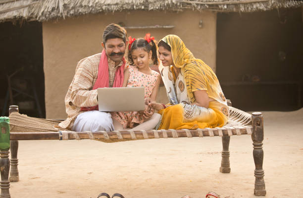 wiejska indyjska rodzina używająca laptopa na tradycyjnym łóżku w wiosce - two parent family asian ethnicity couple computer zdjęcia i obrazy z banku zdjęć