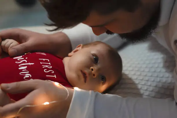 Photo of Man with baby. Young muscular man holding baby and kissing her.