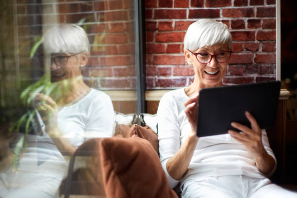 istock Elderly woman using a digital tablet and enjoying herself while sitting comfortably next to a glass window 1093224644