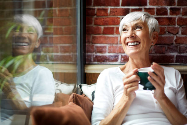 Beautiful elderly woman having a nostalgic moment while drinking a hot drink from a cup