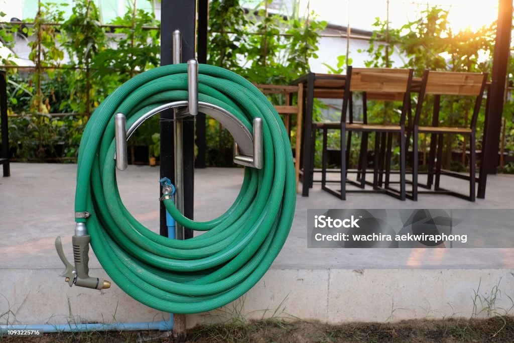 green watering hose in the garden Garden Hose Stock Photo