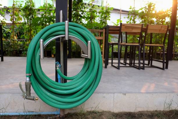 green watering hose in the garden green watering hose in the garden garden hose stock pictures, royalty-free photos & images
