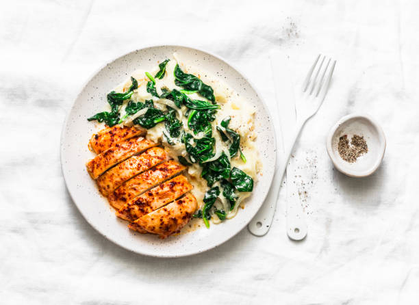 Baked chicken breast, mashed potatoes with creamy spinach on a light background, top view. Comfort food