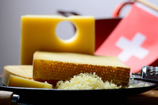 assortment of swiss cheeses emmental or emmentaler medium-hard cheese with round holes, gruyere, appenzeller and raclette used for traditional cheese fondue and gratin and flag of switzerland - cheese emmental cheese switzerland grated imagens e fotografias de stock