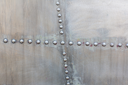 Old silver metal surface of the aircraft fuselage with rivets. Iron plate,steel sheet texture,pattern and background. Aluminum surface of the aircraft fuselage. Smooth rows of rivets.