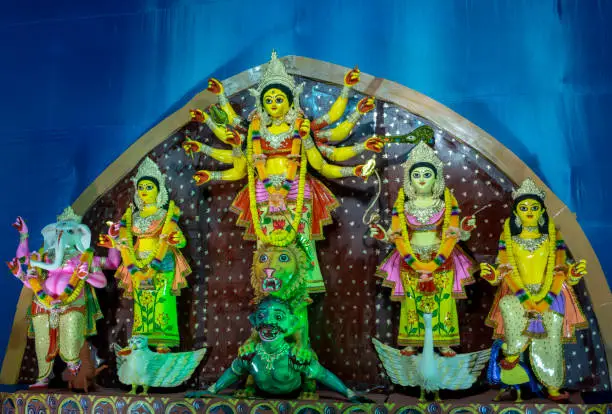 Photo of Goddess Durga idol at decorated Puja pandal, shot at colored light.