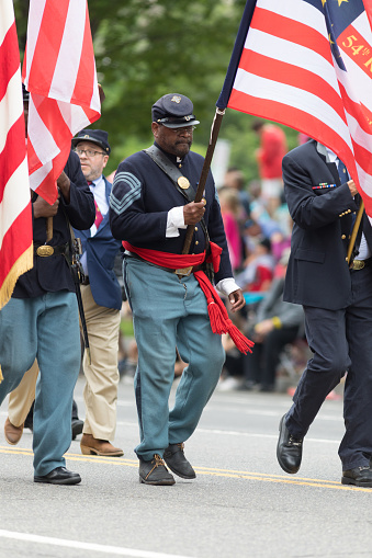 Washington, D.C., USA - May 28, 2018: The National Memorial Day Parade, African american Men dress up as civil war union soldiers, carrying the american flag, walking down constitution avenue