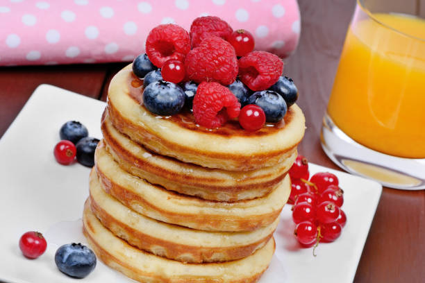 istock Delicious pancakes with berries in a plate and orange juice on table 1093281166
