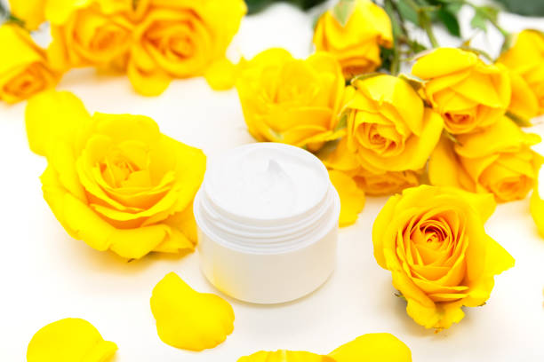 cosmetici botanici aromatici. trattamento spa per la casa per la cura della pelle con petali gialli, fiori di rosa, crema naturale per il viso - merchandise spa treatment botanical spa treatment exfoliation foto e immagini stock