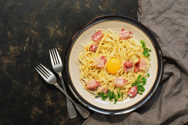 istock Pasta carbonara with parmesan, bacon, raw yolk on a dark rustic background. View from above 1093297968