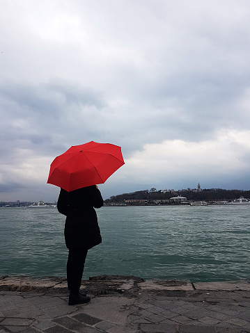 women holding red umbrella at the side of bosphous,istanbul