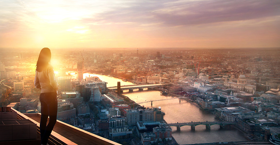 Young woman looking over the City of London at sunset. Future, new business opportunity and business success concept.