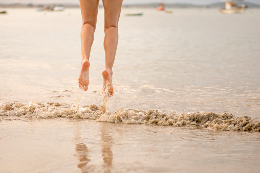 Young woman skipping seven waves at the beach. New year tradition in Brazil. Only feet and legs visible