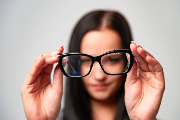 istock Smiling woman in blur background in optical store showing black classic frame for spectacles. 1093312982