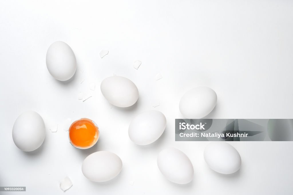 Eggs.One cracked with shell and group of whole unheard eggs  on a white background. Eggs.One cracked with shell egg and group of whole unheard eggs  on a white background.Eggs fresh, unharmed and one broken egg with yellow yolk on a white background.Healthy eating concept of produce organically grown.Can be used as a concept for an egg dieting  for weight loss. Freshness Stock Photo