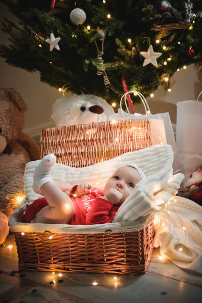 deslizando bebê menino com roupa de natal na cesta natal decoração e luzes piscam ao redor dela. - baby goods flash - fotografias e filmes do acervo