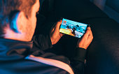 Leisure gamer plays action video game on mobile phone at night