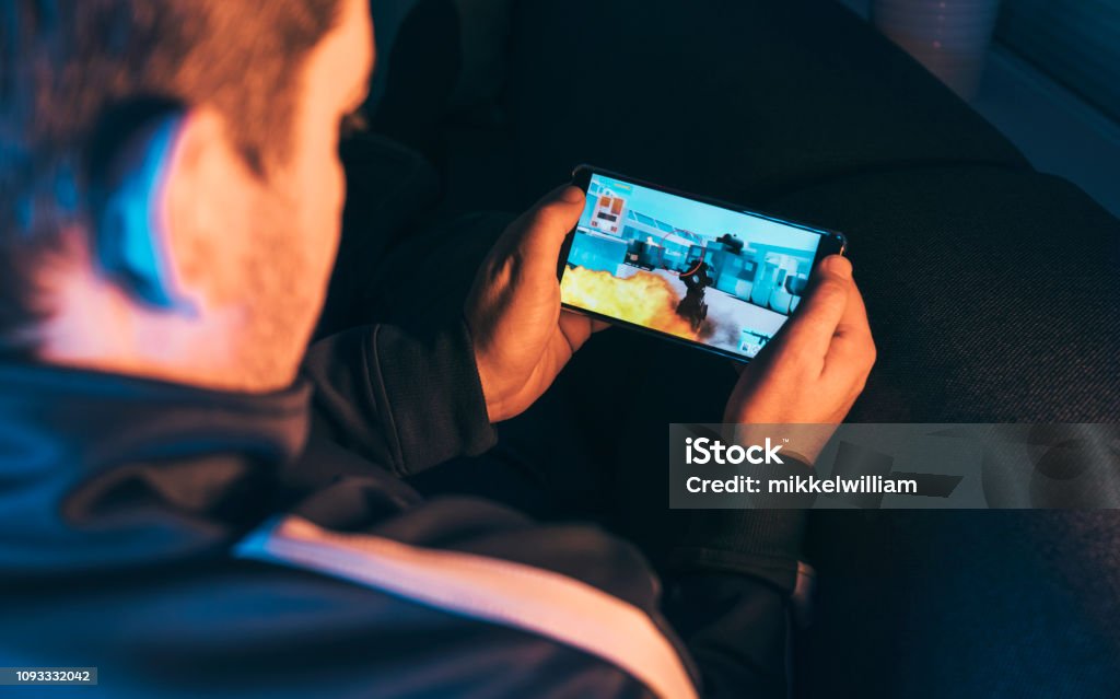 Lazer gamer joga ação vídeo no telemóvel à noite - Foto de stock de Jogo de lazer royalty-free